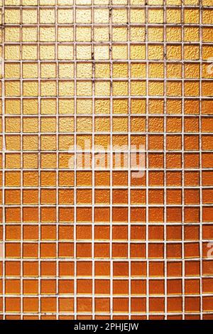 Mur de bâtiment décoré de petits carreaux carrés dorés. Carrelage en verre orange dans une piscine. Arrière-plan texturé Banque D'Images