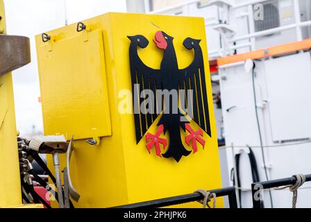 Bensersiel, Allemagne. 25th mars 2023. Le blason fédéral allemand, l'aigle fédéral, est accroché à un navire de la police maritime, amarré à un mur de quai dans le port. Credit: Hauke-Christian Dittrich/dpa/Alay Live News Banque D'Images