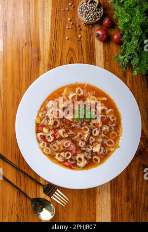 Calamars sautés maison avec sauce Chili épicée dans une assiette blanche sur une table en bois Banque D'Images