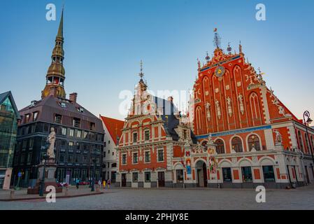 Coucher de soleil sur la place Ratslaukums avec église Saint-Pierre et Maison des Blackheads dans la vieille ville de Riga en Lettonie. Banque D'Images