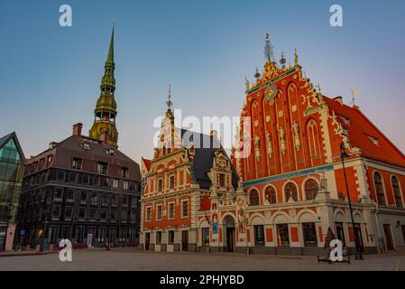 Coucher de soleil sur la place Ratslaukums avec église Saint-Pierre et Maison des Blackheads dans la vieille ville de Riga en Lettonie. Banque D'Images