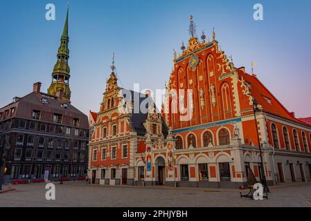 Coucher de soleil sur la place Ratslaukums avec église Saint-Pierre et Maison des Blackheads dans la vieille ville de Riga en Lettonie. Banque D'Images