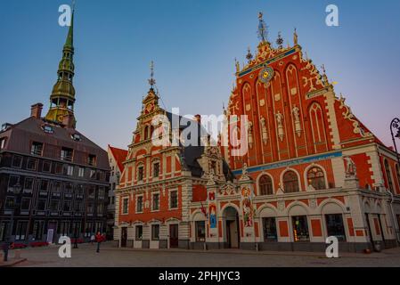 Coucher de soleil sur la place Ratslaukums avec église Saint-Pierre et Maison des Blackheads dans la vieille ville de Riga en Lettonie. Banque D'Images