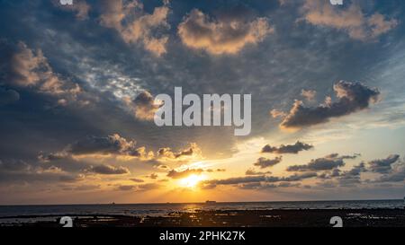 Un coucher de soleil calme et envoûtant dans le ciel nuageux et moelleux au-dessus de la mer Banque D'Images