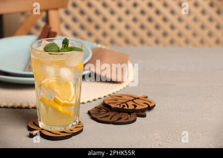 Verre de limonade et dessous de verre en forme de feuilles sur table en bois gris Banque D'Images
