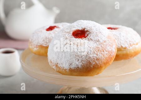 Délicieux beignets avec de la gelée et du sucre en poudre sur un présentoir à pâtisseries, gros plan Banque D'Images