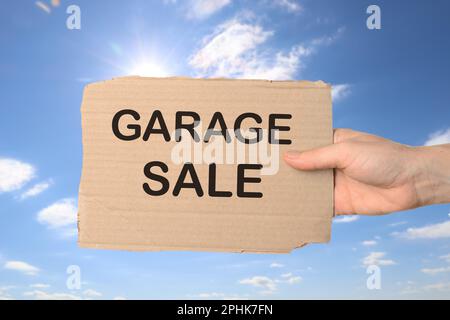 Femme tenant signe avec texte VENTE DE GARAGE contre ciel bleu Banque D'Images