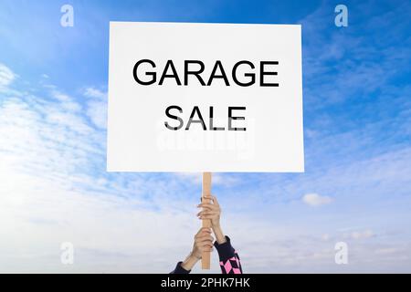 Femme tenant signe avec texte VENTE DE GARAGE contre ciel bleu Banque D'Images