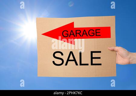Femme tenant signe avec texte VENTE DE GARAGE contre ciel bleu Banque D'Images