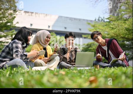 Un groupe de jeunes étudiants asiatiques, heureux et intelligents, parlent et brainstorming sur leur projet scolaire dans le parc du campus ensemble. Banque D'Images