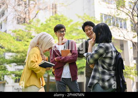 Un groupe de jeunes étudiants asiatiques joyeux et heureux apprécient de parler ensemble dans le parc du campus. Banque D'Images