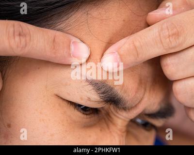 Gros plan de la femme asiatique en appuyant sur des boutons sur son visage. Concept de style de vie de soin de la peau Banque D'Images