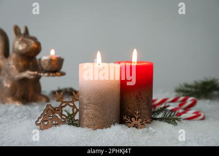 Bougies allumées et décoration de Noël sur neige artificielle Banque D'Images