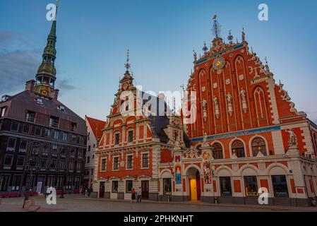 Coucher de soleil sur la place Ratslaukums avec église Saint-Pierre et Maison des Blackheads dans la vieille ville de Riga en Lettonie. Banque D'Images