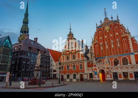 Coucher de soleil sur la place Ratslaukums avec église Saint-Pierre et Maison des Blackheads dans la vieille ville de Riga en Lettonie. Banque D'Images