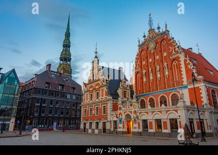 Coucher de soleil sur la place Ratslaukums avec église Saint-Pierre et Maison des Blackheads dans la vieille ville de Riga en Lettonie. Banque D'Images