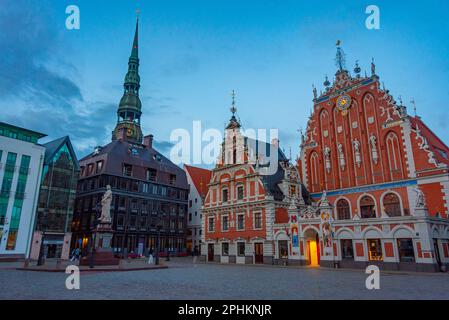 Coucher de soleil sur la place Ratslaukums avec église Saint-Pierre et Maison des Blackheads dans la vieille ville de Riga en Lettonie. Banque D'Images