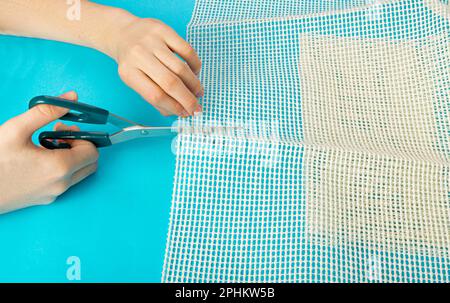 Sous-couche antidérapante pour empêcher les tapis de bouger, découpe du filet en caoutchouc pour le placement sous le tapis sur fond bleu vue de dessus Banque D'Images