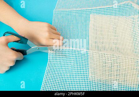 Sous-couche antidérapante pour empêcher les tapis de bouger, découpe du filet en caoutchouc pour le placement sous le tapis sur fond bleu vue de dessus Banque D'Images