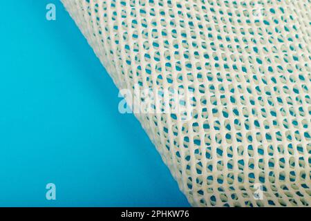 Sous-couche antidérapante pour empêcher les tapis de bouger, filet en caoutchouc pour les placer sous le tapis sur fond bleu Banque D'Images