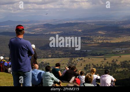 Groupe de spectateurs sur Tamborine Mountain observant des deltaplane et des parapentes qui dévolent et survolent le bord. Queensland, Australie. Banque D'Images