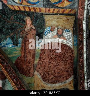 Une femme, peut-être une reine ou une princesse, se tient à côté d'un homme barbu, peut-être un roi ou un prince, qui est couché dans son lit les yeux fermés. Fresque gothique tardive dans le cloître médiéval à côté du Duomo di Bressanone (cathédrale de Santa Maria Assunta) à Bressanone-Brixen, Tyrol du Sud, Trentin-Haut-Adige, Italie. Banque D'Images
