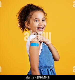 Heureux, portrait et enfant avec un plâtre dans un studio pour une blessure, une blessure ou une blessure sur son bras. Bonheur, sourire et santé fille enfant modèle posant avec un Banque D'Images