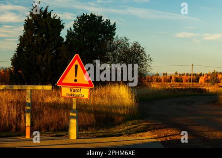 Un panneau, conditions glissantes en finnois dans un endroit de nettoyage de tapis au coucher du soleil . Signe d'avertissement de conditions glissantes. Banque D'Images