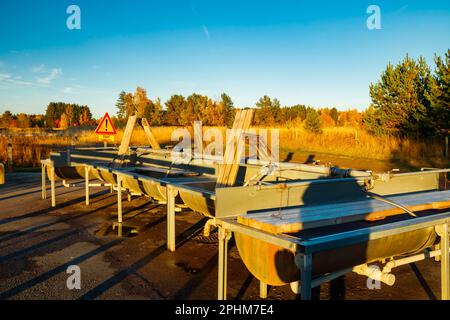 Un lieu de lavage de tapis en Finlande au coucher du soleil. Un panneau, conditions glissantes en finnois dans un endroit de nettoyage de tapis au coucher du soleil . Signe d'avertissement de Banque D'Images