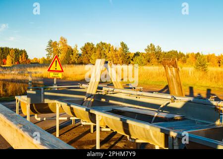 Un lieu de lavage de tapis en Finlande au coucher du soleil. Un panneau, conditions glissantes en finnois dans un endroit de nettoyage de tapis au coucher du soleil . Signe d'avertissement de Banque D'Images