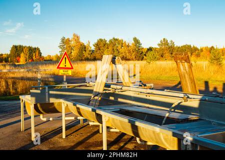 Un lieu de lavage de tapis en Finlande au coucher du soleil. Un panneau, conditions glissantes en finnois dans un endroit de nettoyage de tapis au coucher du soleil . Signe d'avertissement de Banque D'Images