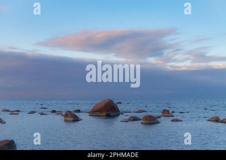 Rochers sur les rives de la mer Baltique. Coucher de soleil nuageux. Banque D'Images