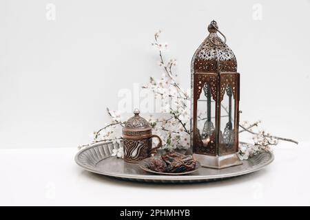 Ramadan Kareem encore la vie. Dattiers, fleurs blanches tasse de thé et lanterne marocaine brillante sur plaque argentée. Arrière-plan de paramétrage de la table. Prune cerise Banque D'Images