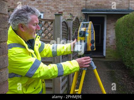 Un arpenteur effectue son travail avec une station totale ou un instrument / machine de théodolite sur certaines zones de logement locales. Banque D'Images