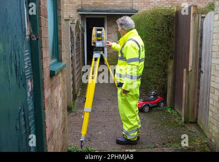 Un arpenteur effectue son travail avec une station totale ou un instrument / machine de théodolite sur certaines zones de logement locales. Banque D'Images