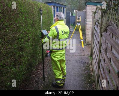 Un arpenteur effectue son travail avec une station totale ou un instrument / machine de théodolite sur certaines zones de logement locales. Banque D'Images