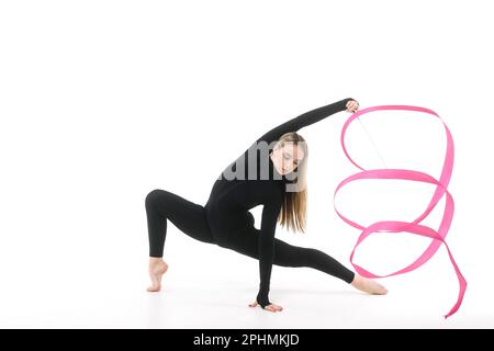 Gimnast fille dans un costume noir ajusté avec un ruban rose sur un fond blanc Banque D'Images