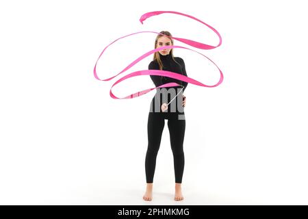 Gimnast fille dans un costume noir ajusté avec un ruban rose sur un fond blanc Banque D'Images