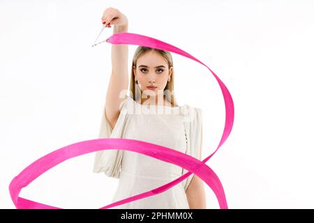 Gymnaste fille vêtue d'une robe de soirée avec un ruban rose sur fond blanc Banque D'Images