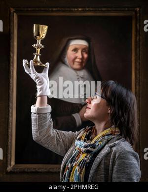 La responsable des collections spéciales, le Dr Hannah Thomas, tient le calice de 1630s avec des représentations des stations de la Croix exposées au couvent du Bar à York, le plus ancien couvent vivant du Royaume-Uni, dans le cadre d'une exposition pour Pâques. Date de la photo: Mercredi 29 mars 2023. Banque D'Images