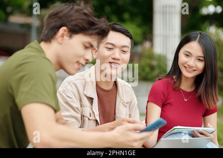 Groupe d'étudiants discutant de la nouvelle application sur smartphone Banque D'Images