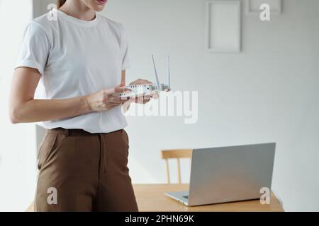 Image rognée d'une jeune femme qui définit un routeur wi-fi pour pouvoir travailler à domicile Banque D'Images