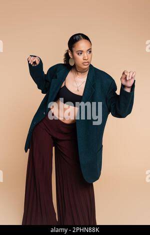 jeune afro-américain modèle en bleu foncé blazer woolen gestant isolé sur beige, image de stock Banque D'Images