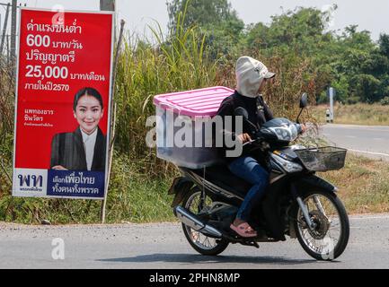 Nakhon Sawan, Thaïlande. 29th mars 2023. Une femme roule à moto le long d'une route dans la province de Nakhon Sawan, au nord de Bangkok, après une affiche de campagne de Paetongtarn Shinawatra, le Parti Phue Thai et le candidat électoral au poste de Premier ministre. Les prochaines élections générales en Thaïlande auront lieu sur 14 mai 2023. Crédit : SOPA Images Limited/Alamy Live News Banque D'Images