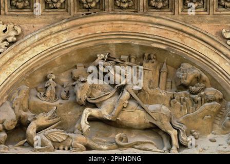 Bohemian St George and Dragon : le saint monté, aux cheveux longs, portant une armure typique du début de 1500s, se dresse dans ses étriers, prêt à frapper le monstre ailé avec une épée massive : Remplacement relief sculpté fin de style gothique sur la porte sud de la basilique Saint-Georges dans le château de Prague, Hradčany, Prague, Tchéquie ou République Tchèque. Banque D'Images