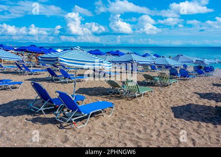 Chaises longues et parasols sur une plage dans la ville de Rhodes en Grèce. Banque D'Images