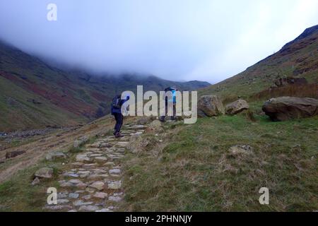 Deux hommes (randonneurs) marchant sur le chemin d'Esk Hause via Stockley Bridge à Scafell Pike de Seathwaite à Borrowdale dans le parc national de Lake District. Banque D'Images