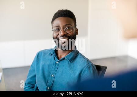 Homme d'affaires noir discutant avec une collègue féminine lors d'une réunion, homme et femme ayant une conversation, discutant du travail au bureau Banque D'Images