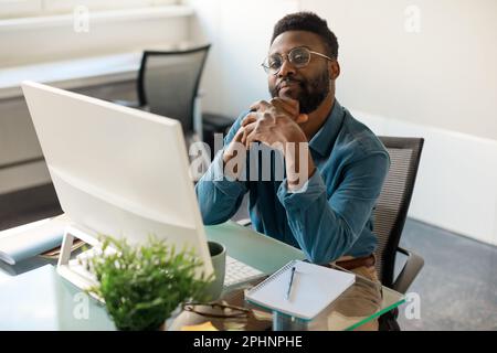 Homme d'affaires afro-américain ou homme d'affaires assis sur le lieu de travail devant l'ordinateur et regardant la caméra Banque D'Images