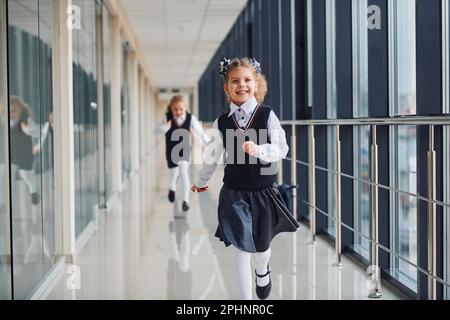 Filles scolaires en uniforme courant ensemble dans le couloir. Conception de l'éducation Banque D'Images